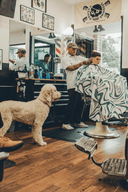A barber with a customer wearing the Aurora Barber Cape by High Top Capes
